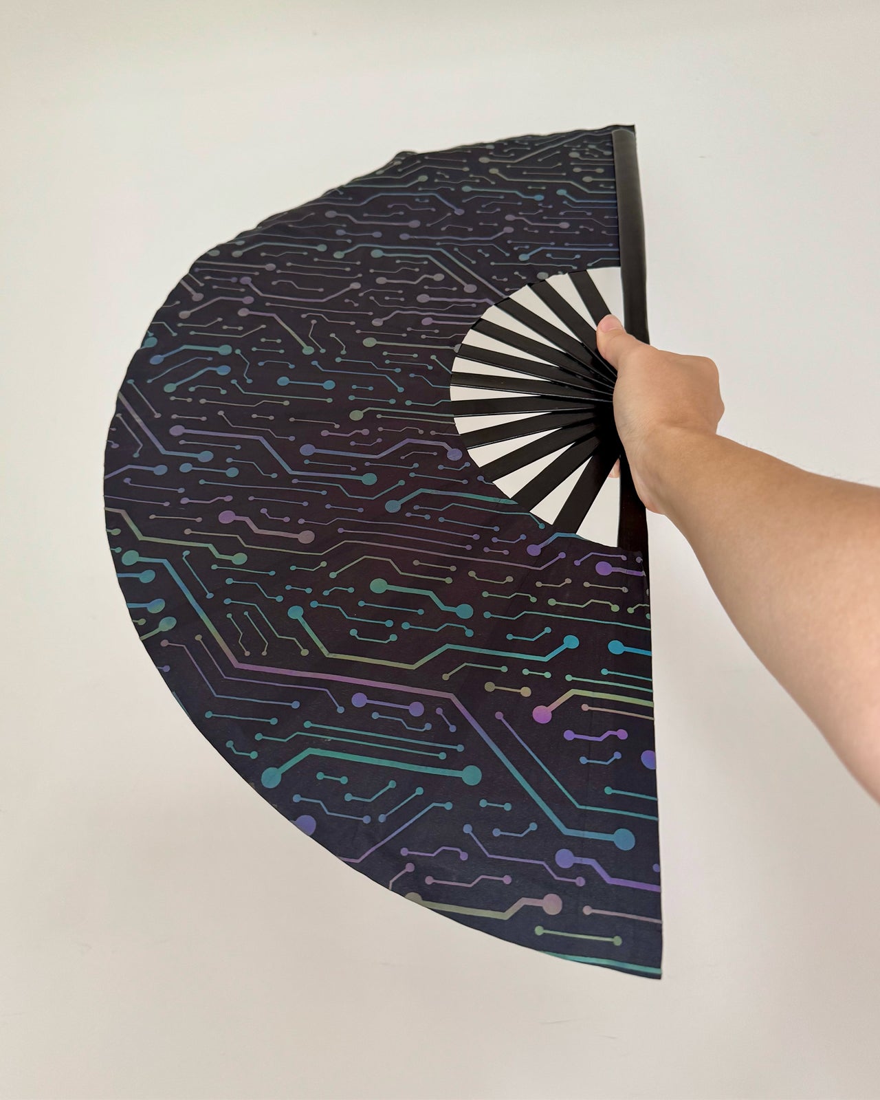 Electric Eden's reflective hand fan showcasing UV glow under blacklight